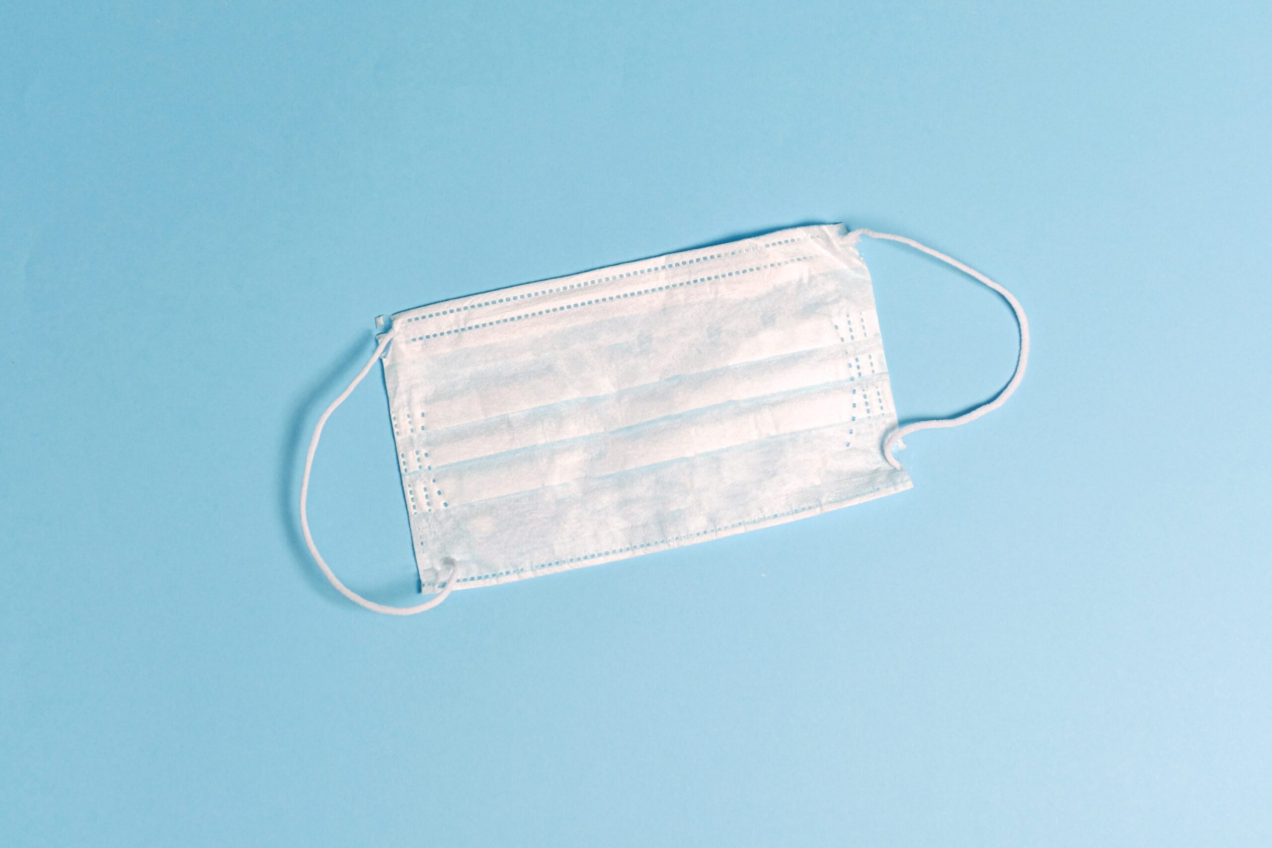 An image of a single surgical facemask lying on a table